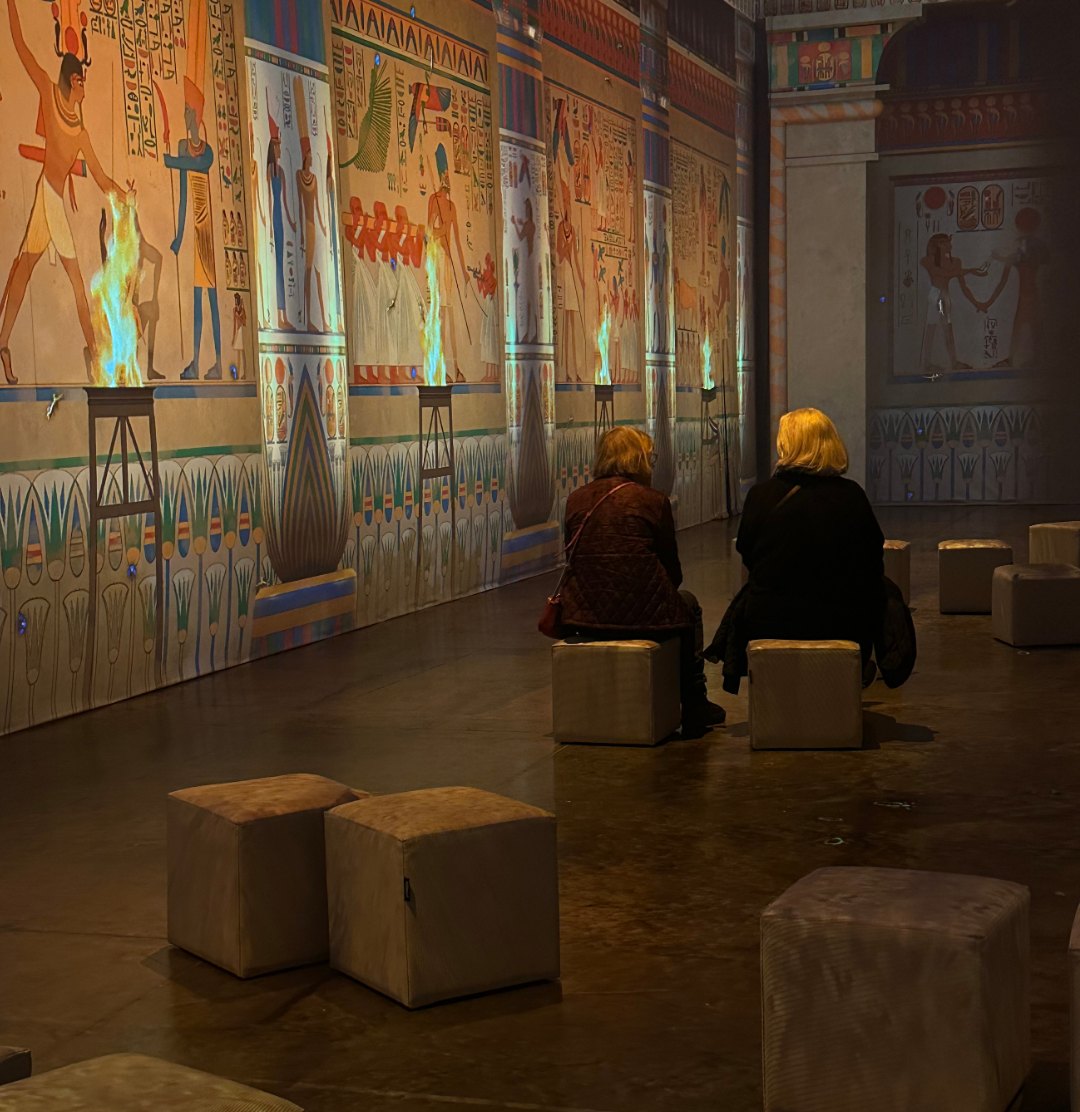 Besökare i en korridor med projicerade egyptiska väggmålningar